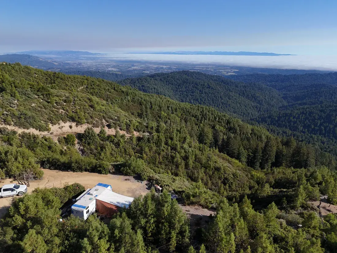 Aerial view of a cleared bench and structure on the ridge with the valley beyond